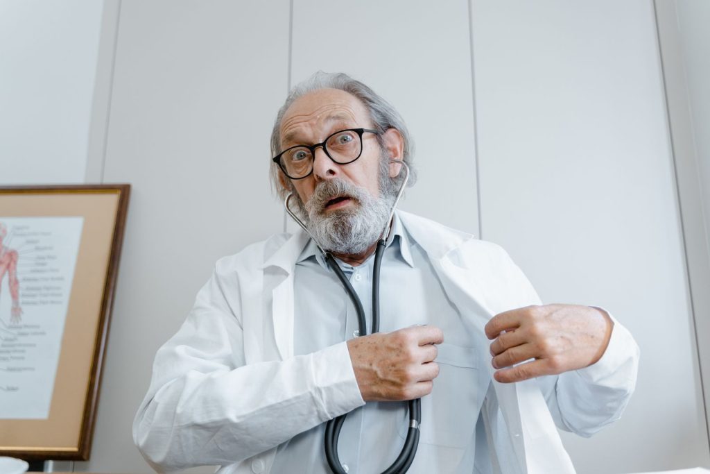 Surprised elderly doctor wearing lab coat and stethoscope indoors.