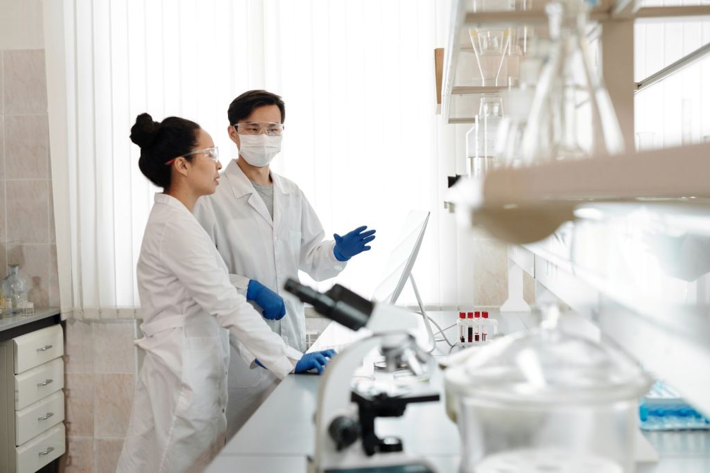Scientists in a lab discussing experiments and wearing safety gear.