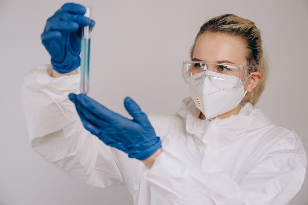 Woman scientist in protective gear holding a test tube during a scientific experiment.