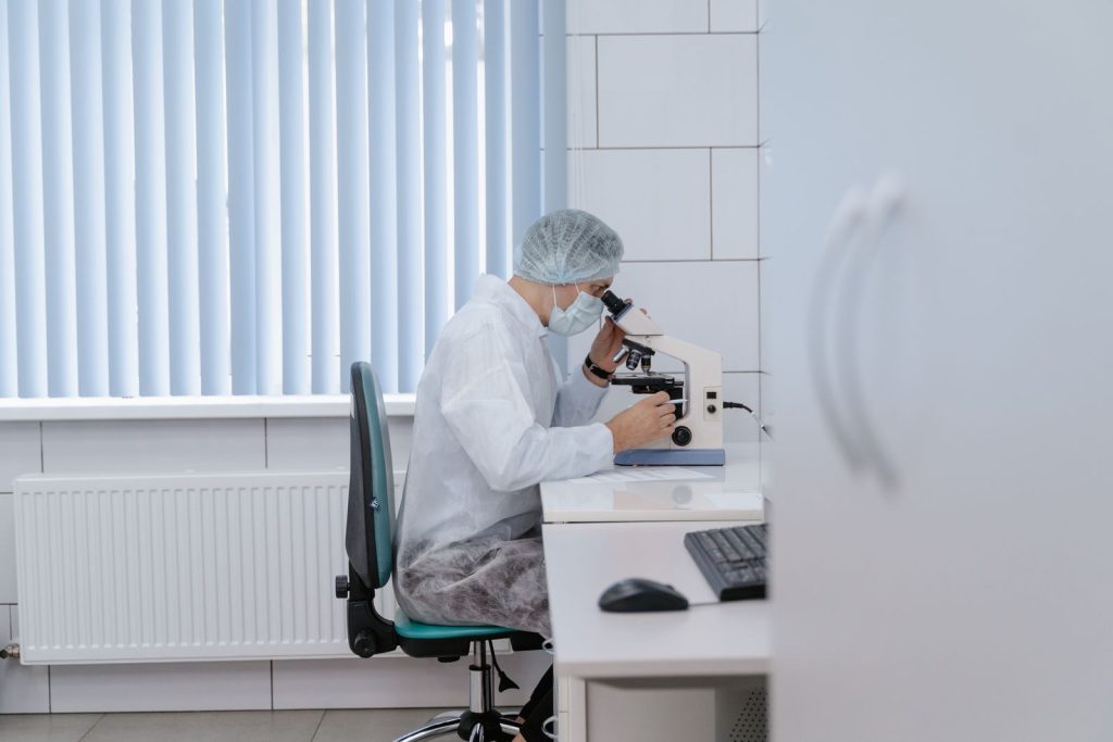Scientist working in a lab using a microscope for scientific research and analysis.