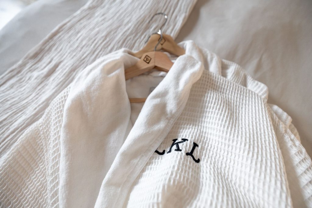 Elegant white robe with embroidery on hanger, showcasing luxury and comfort.