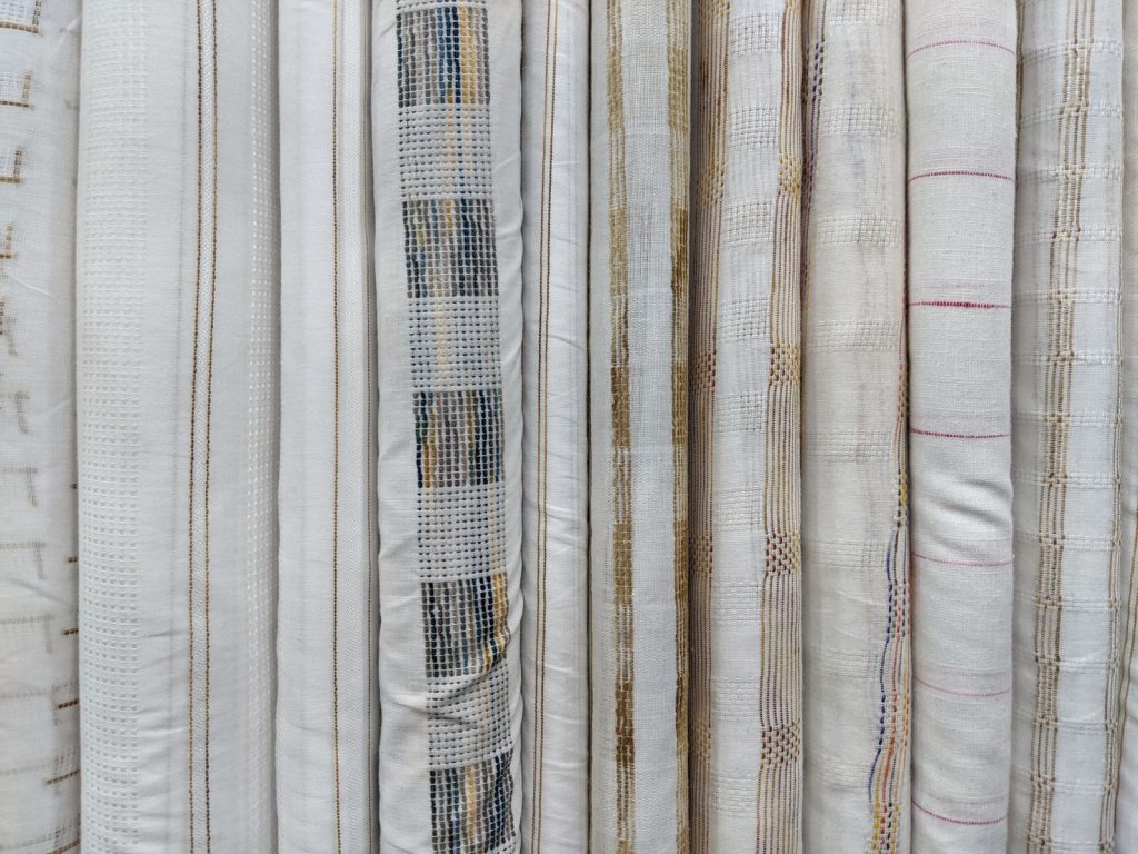 Monochrome fabric rolls displaying elegant, subtle patterns and textures for interior design.