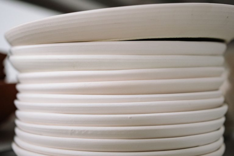 A close-up view of stacked white porcelain plates in natural light.