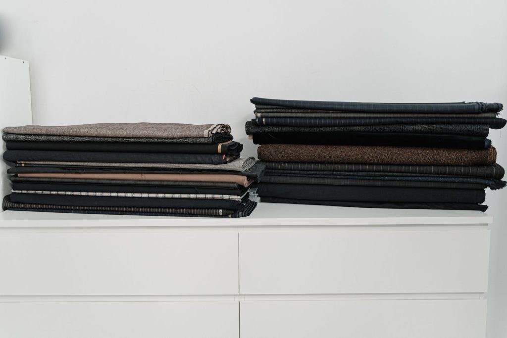 Cleanly stacked textiles on a white cabinet, ideal for fashion designers and sewing projects.