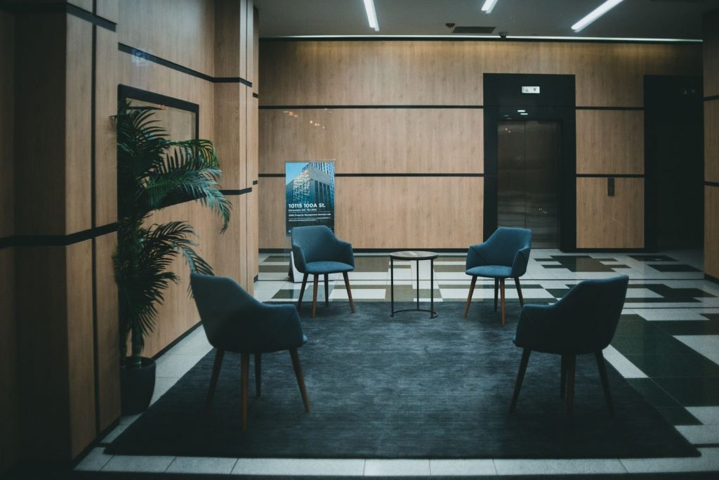 A stylish office lobby featuring chic chairs and a minimalistic design with a neutral tone.