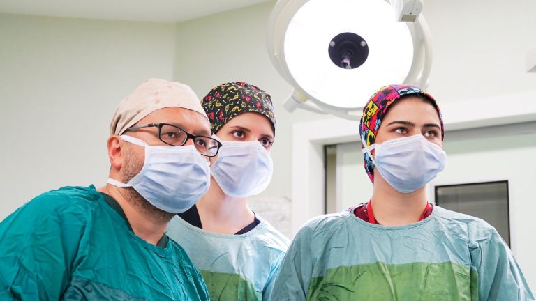 Team of surgeons focused during a procedure in a well-lit operating room.