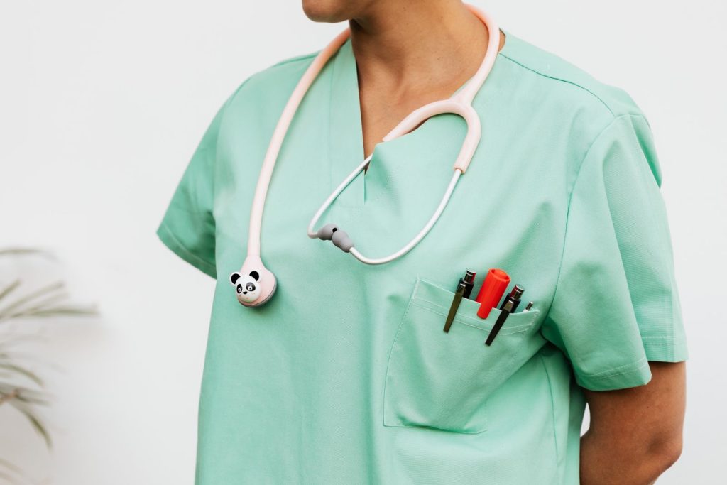 Close-up of a doctor in scrubs with a panda themed stethoscope and pocket pens.