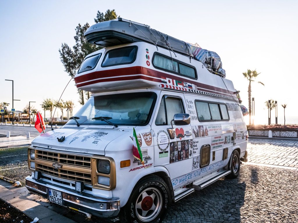 Retro camper van with decorations, parked in a sunny urban area, showcasing adventure vibes.