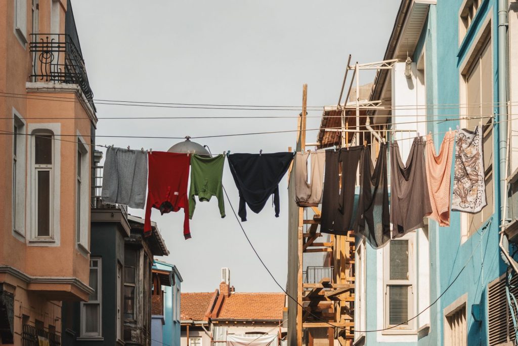 Brightly colored clothes hanging between buildings on a sunny day in a city street.