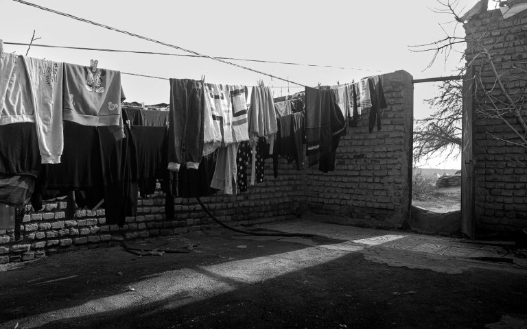 Sunlit yard featuring clothes drying on a line, captured in timeless black and white.