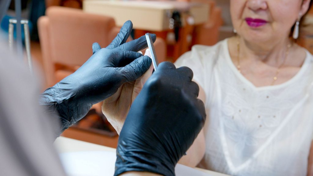 Senior woman enjoys a manicure at a salon, highlighting beauty and care in a gentle setting.