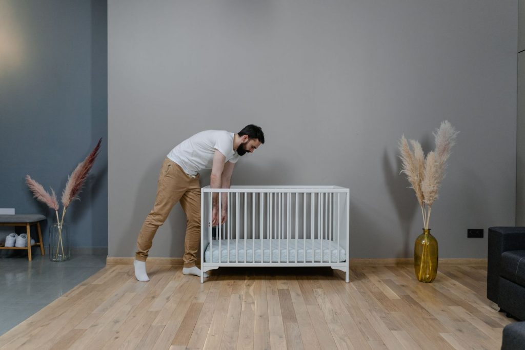 A father tending to a baby in a stylish, modern nursery with soft decor and natural light.