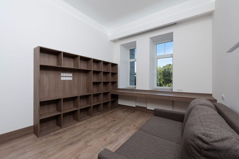 Spacious minimalist living room with wood furnishings and large windows.