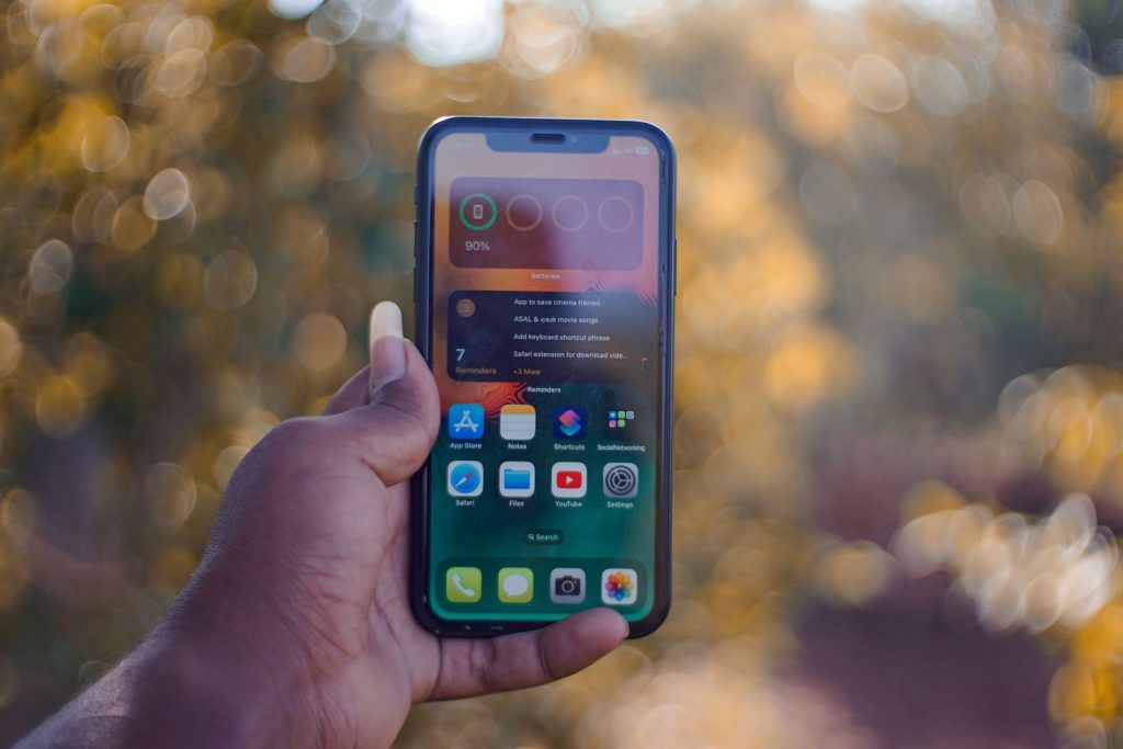 Detailed view of a smartphone held by a person with a blurred outdoor background.