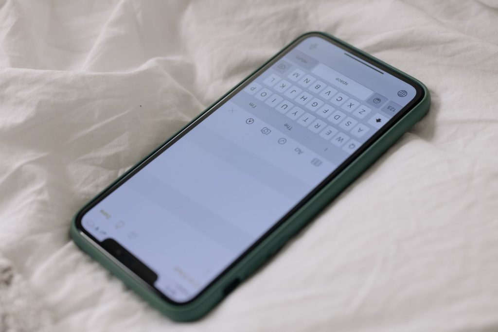 A smartphone with a touchscreen lays on white linen bedsheet, showcasing modern technology.