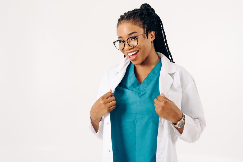 Confident female doctor smiling in a white coat with teal scrubs, embodying professionalism and approachability.
