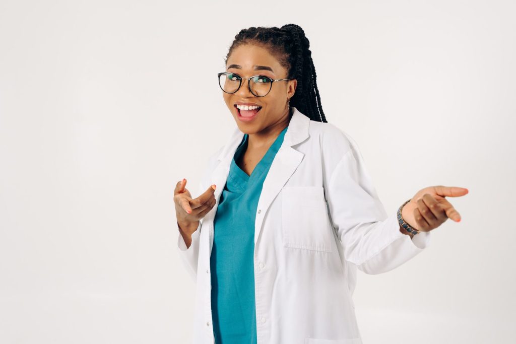 Smiling female doctor pointing in a cheerful pose on a white background.