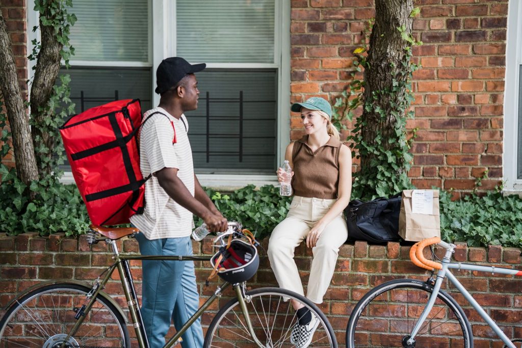 Food delivery bicycle courier interacting with client outdoors. Urban delivery service concept.