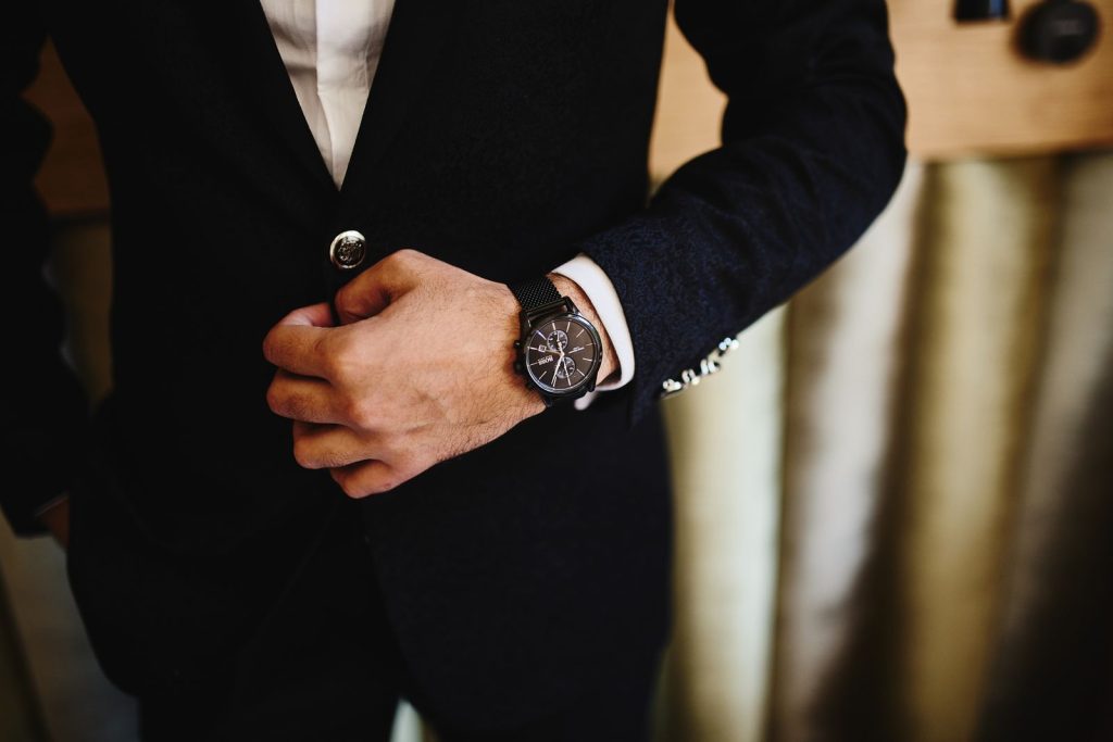 Close-up of a man in a black suit, showcasing a stylish wristwatch. Perfect for fashion and business themes.