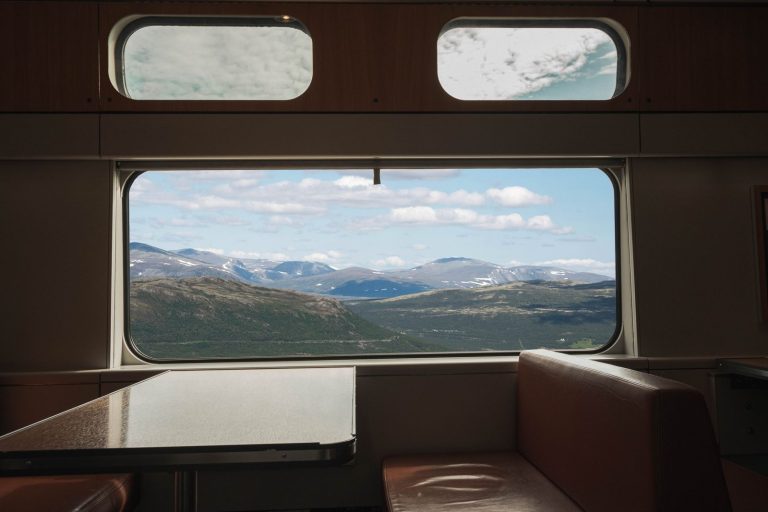 View from a train window overlooking vast mountainous landscape, capturing travel serenity.