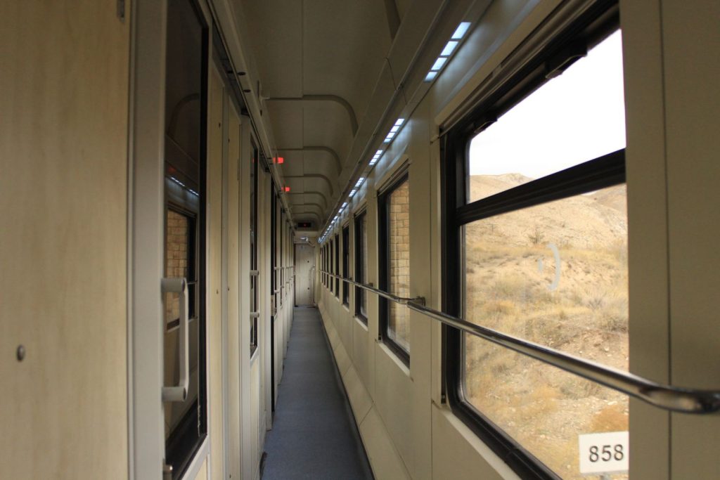 A long corridor inside a train traveling through Kars, Türkiye, showcases outdoor scenery.