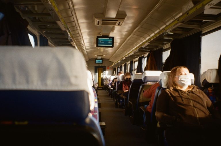 Passengers on a train practicing social distancing and wearing masks during the pandemic.
