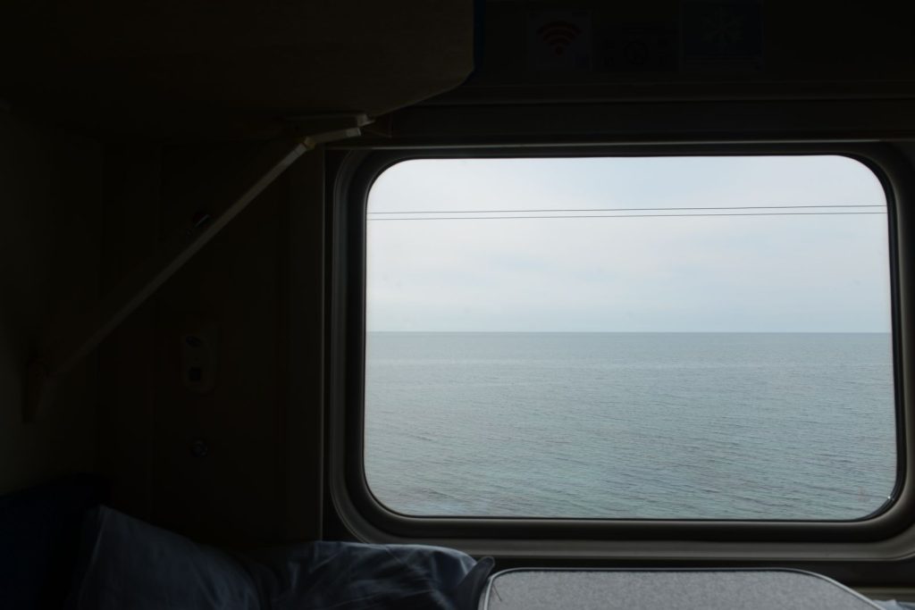 A tranquil view of the sea from a train window, capturing peaceful travel vibes.
