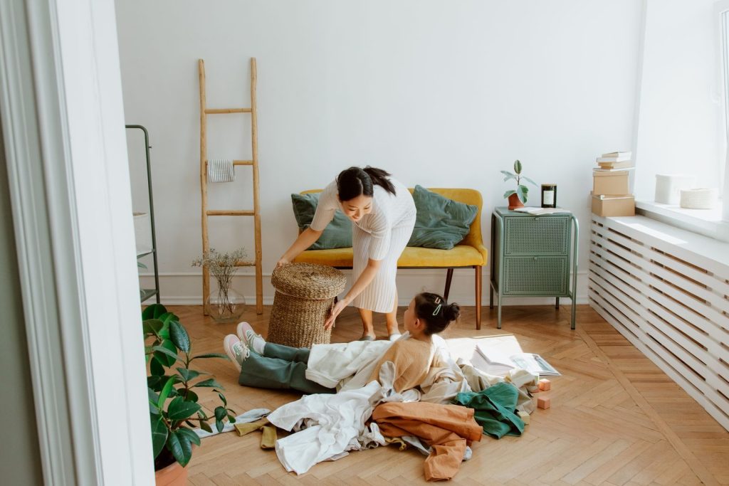 A joyful moment between mother and daughter playing with clothes in a cozy living room.