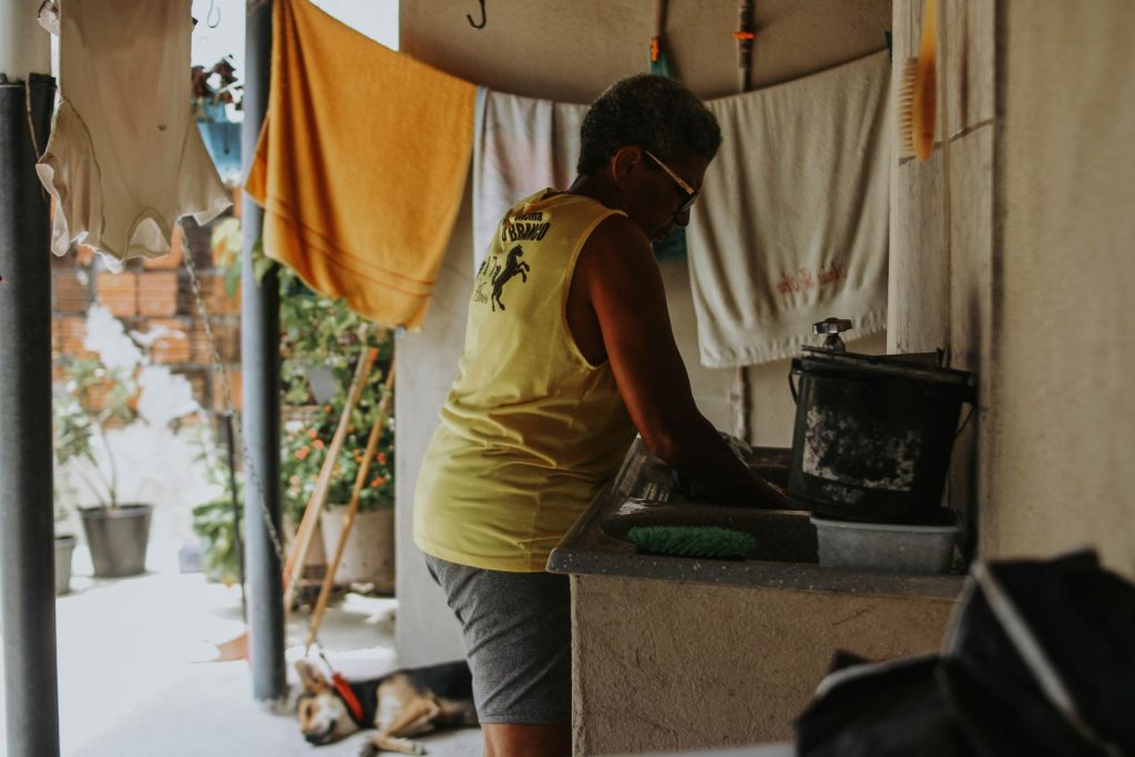 An African American woman washing clothes outdoors in a summer yard.
