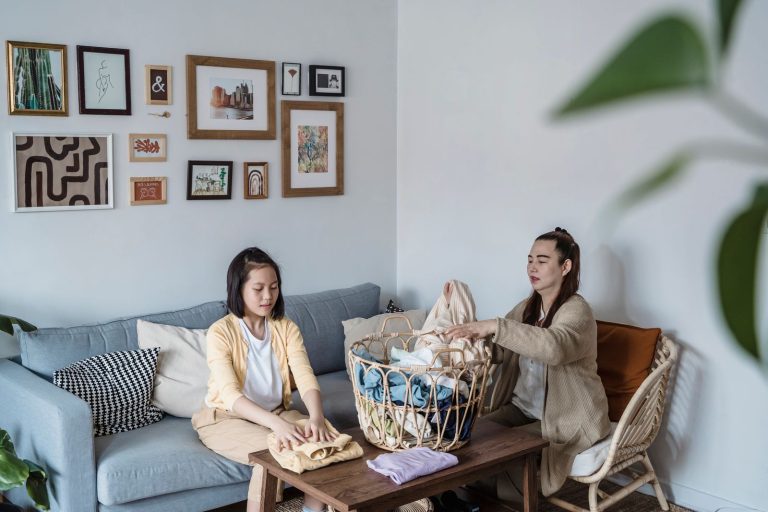 A mother and daughter engaged in folding laundry on a comfortable sofa, enhancing family bonding.