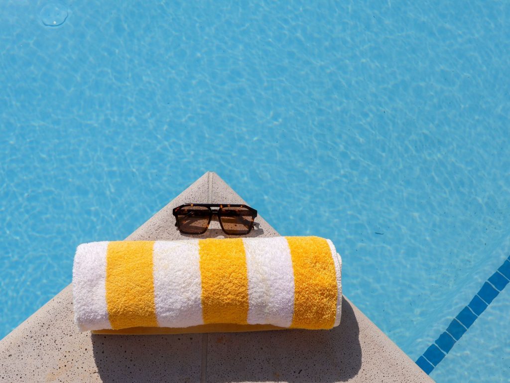 Relax by the pool with striped towel and sunglasses under the summer sun.