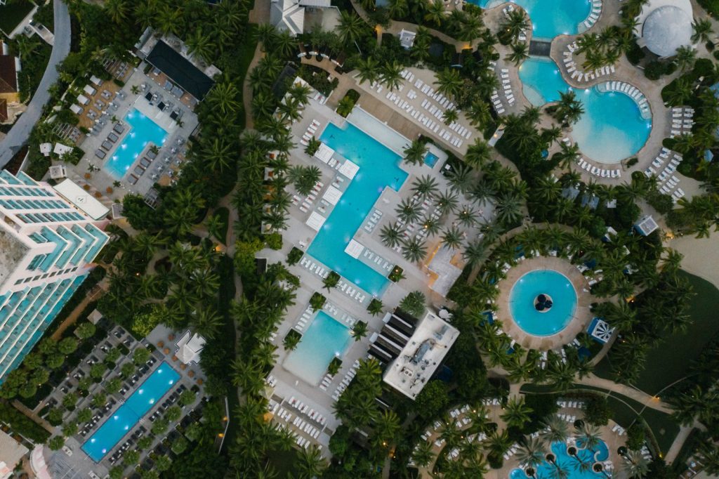Aerial view of a luxury resort featuring swimming pools, palm trees, and elegant architecture at a tropical destination.