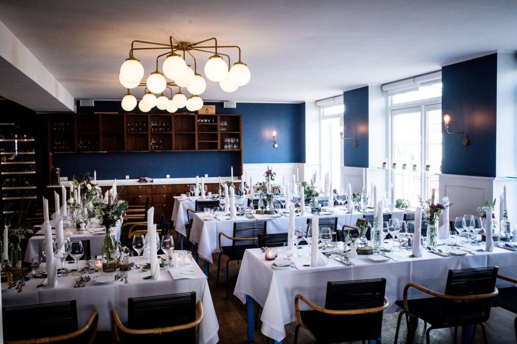 Luxurious dining room set up with tables, chairs, and chandeliers for a formal event.