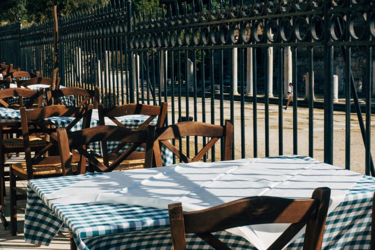 Rustic outdoor seating at a charming café with wooden chairs and checkered tablecloths.