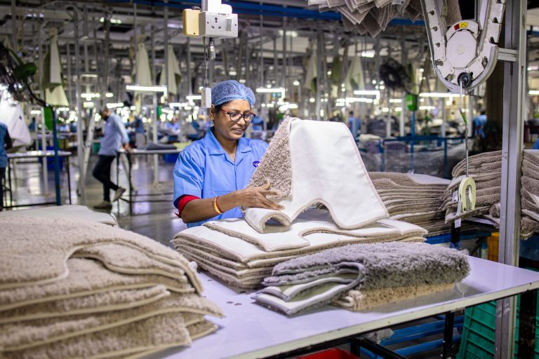 Woman in factory setting organizing textile materials, highlighting blue collar work environment.