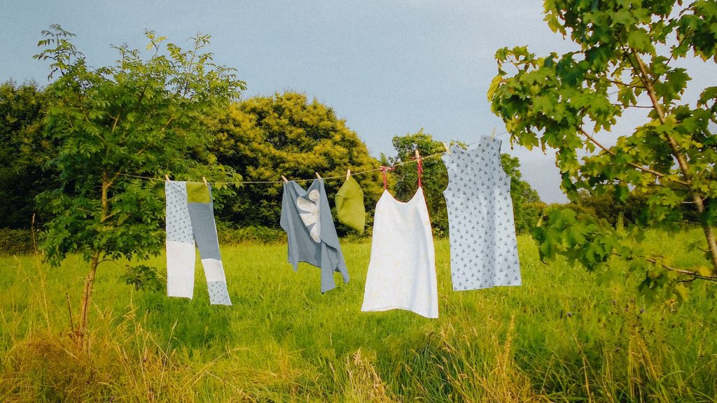 Colorful dresses hanging on a clothesline in a vibrant summer countryside setting.