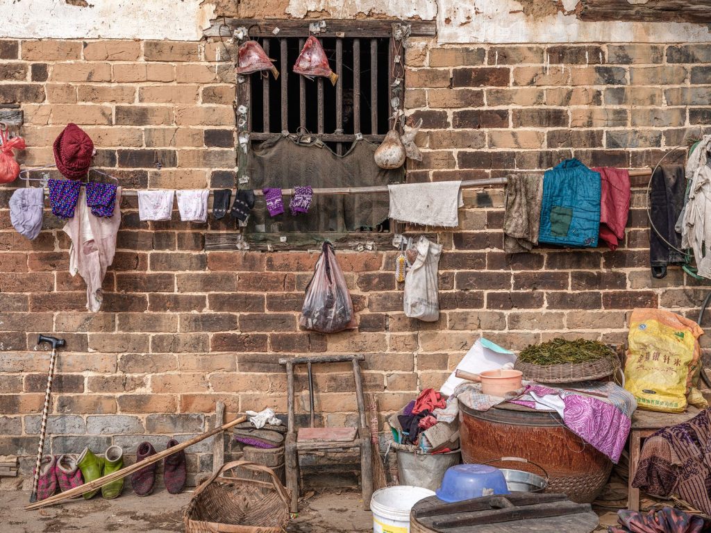 A rustic scene with clothes drying on a rural brick wall and various daily items.
