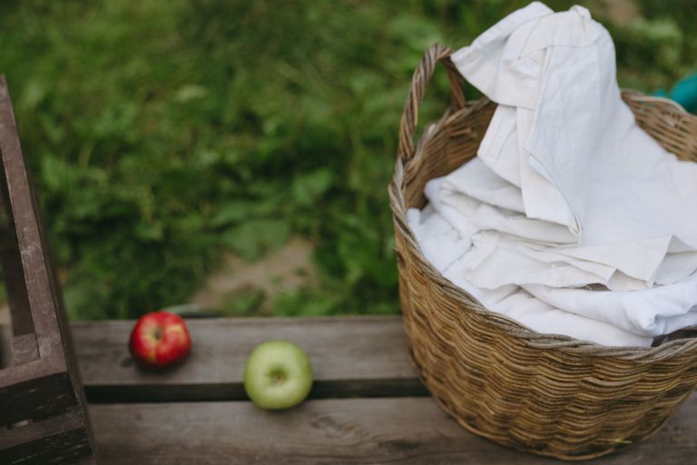 A rustic outdoor setting featuring apples and a wicker laundry basket on wooden surface.