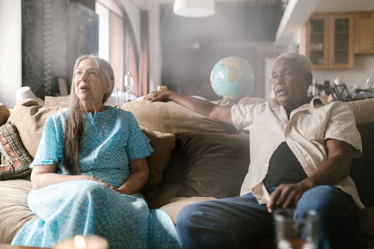 Senior couple sitting on sofa indoors, enjoying a peaceful moment together.