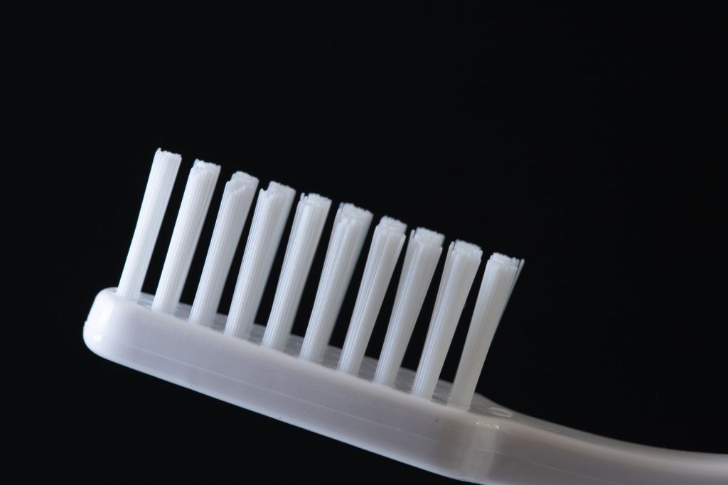 Detailed close-up of a white toothbrush on a black background, ideal for dental hygiene concepts.