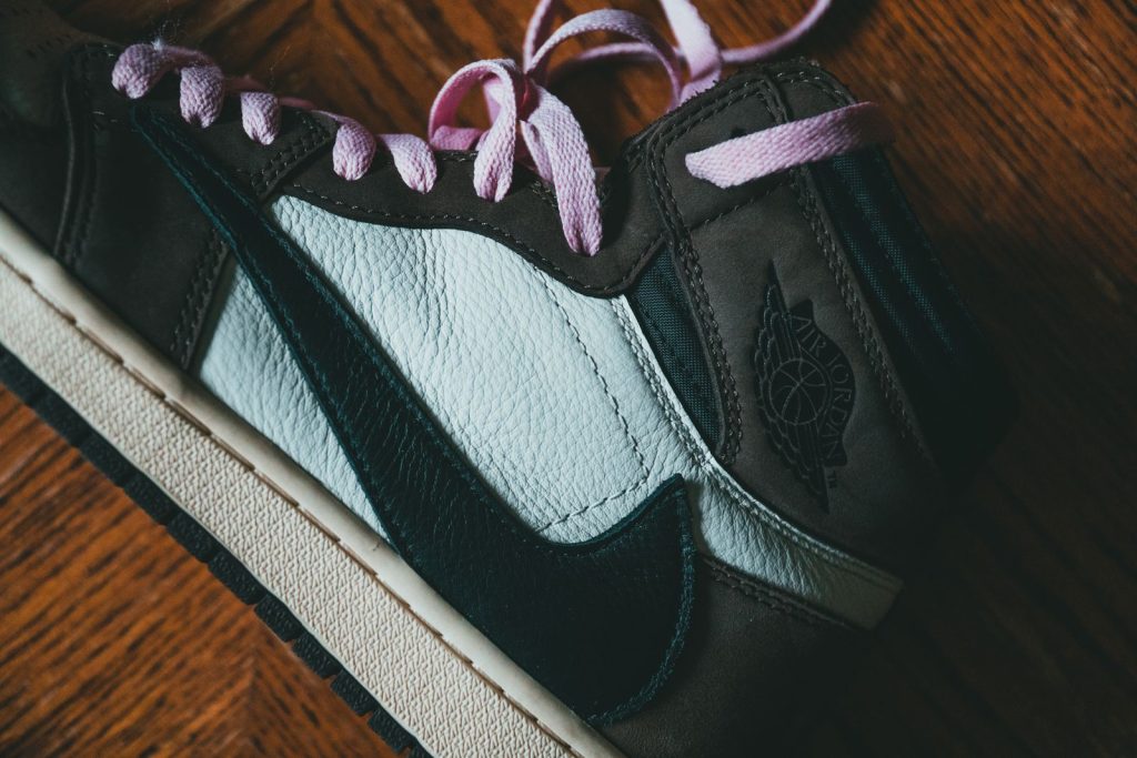 Top view of close up of modern black footwear with pink laces placed on wooden surface