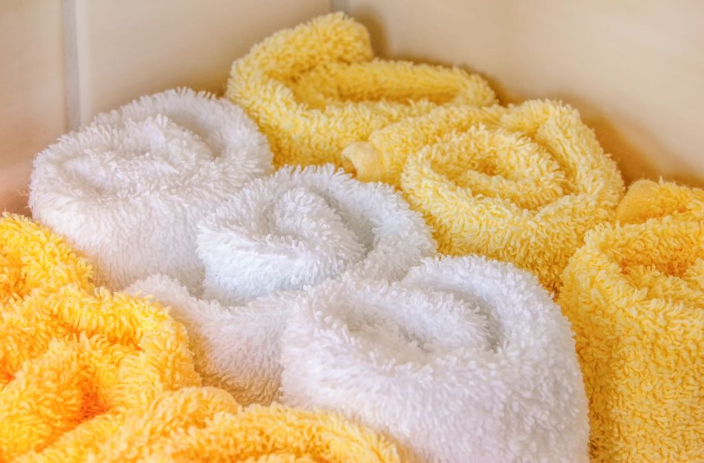 Neatly arranged rolled white and yellow towels in a bathroom setting for hygiene and decor.