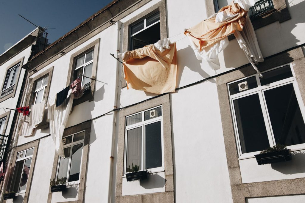 Sunlit urban facade in Porto, Portugal with hanging laundry drying on a clothesline.