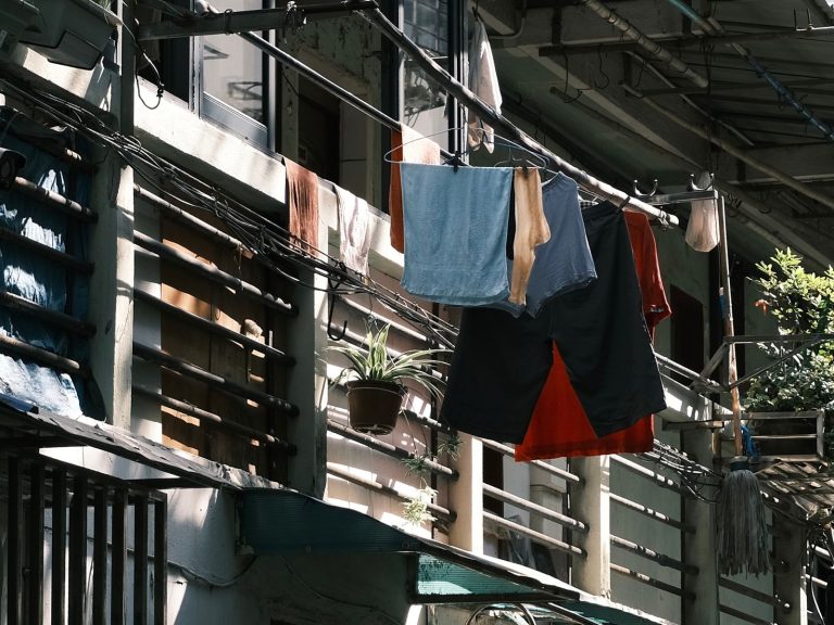 Casual clothing and textiles drying on outdoor balcony in urban area.
