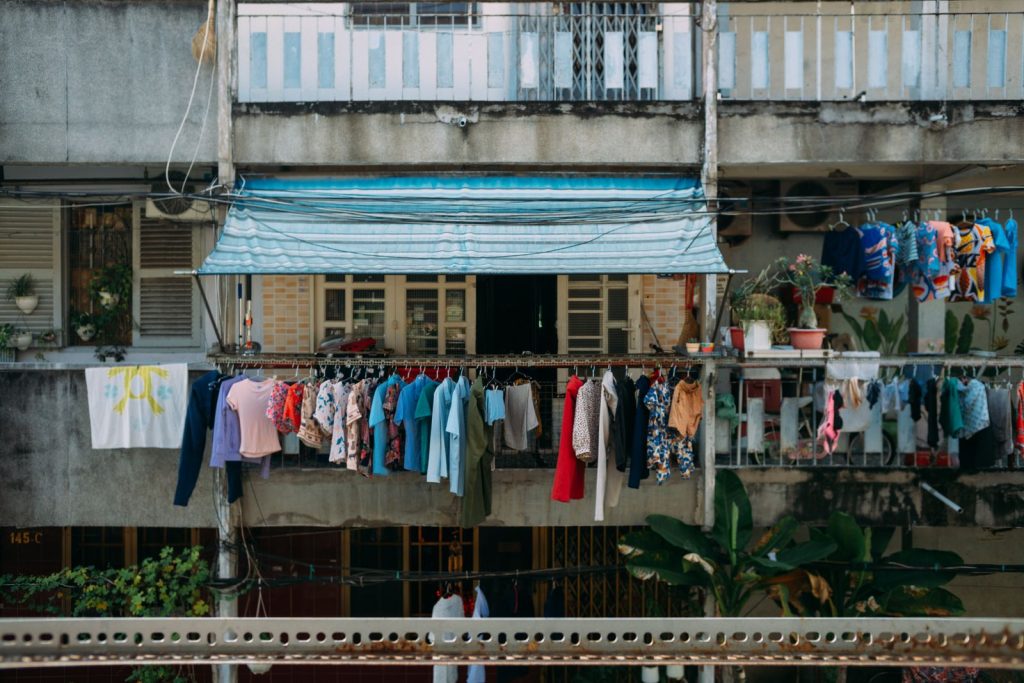 Vibrant clothes hung on an outdoor balcony against urban apartment facade.