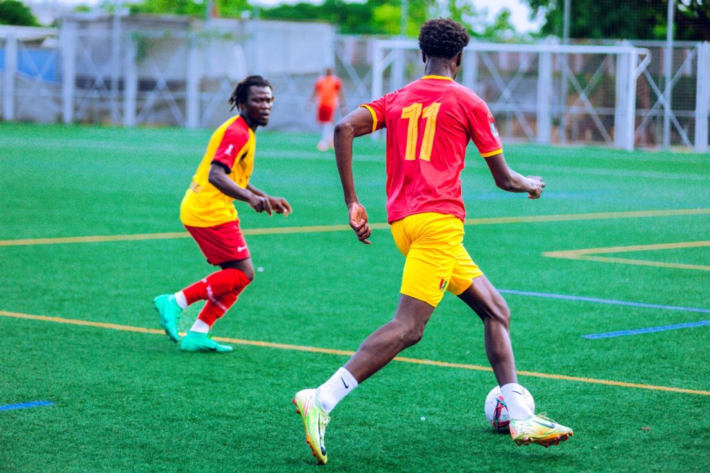 Two players in colorful jerseys compete on a vibrant green soccer field.