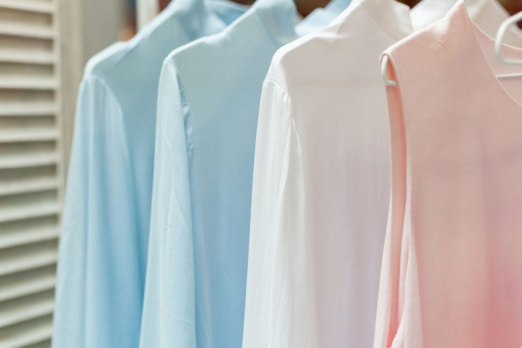 Row of different female apparel made of natural materials and hanging on racks in boutique