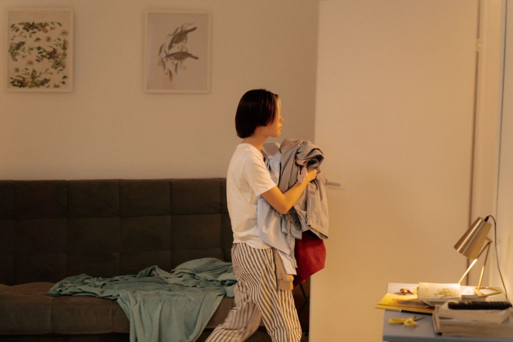 A woman carrying laundry across a cozy, well-lit room with modern decor.