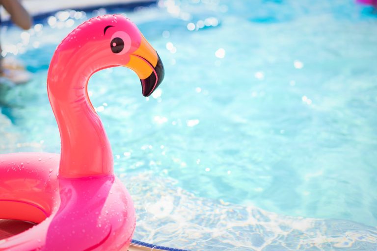 Close-up of a pink flamingo pool float basking in a sunlit swimming pool, perfect for summer vibes.