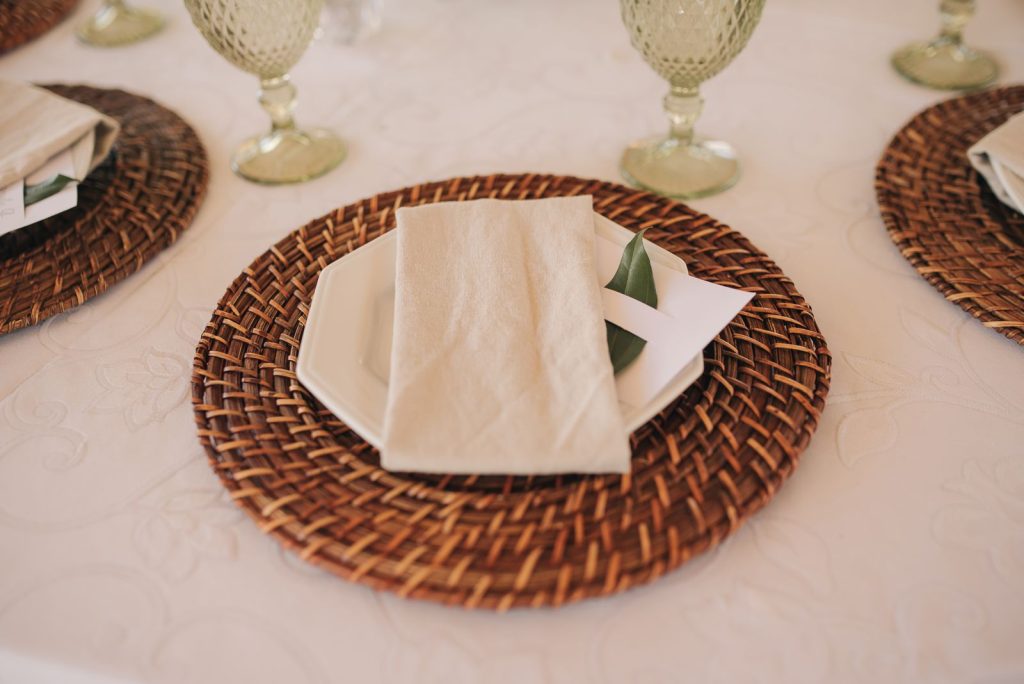 A sophisticated table setup featuring wicker mats, ceramic plates, and stylish glassware.